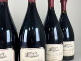 six bottles of wine are lined up on a table