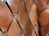 a close up of a brown leather bag with rivets on it