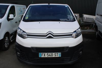 une camionnette blanche garée dans un parking à côté d'autres camionnettes