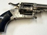 un revolver argenté avec une poignée noire sur une surface blanche