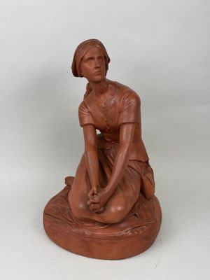 statue d'une femme assise sur un rocher, les mains posées sur les genoux