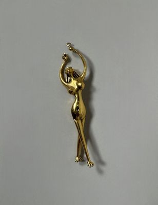 a gold statue of a woman holding a ball on a white surface
