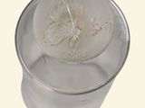 a glass jar with a butterfly on it on a white background