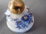 a blue and white vase with a gold ball on top of it