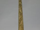 carved obelisk on a black stand with a white background
