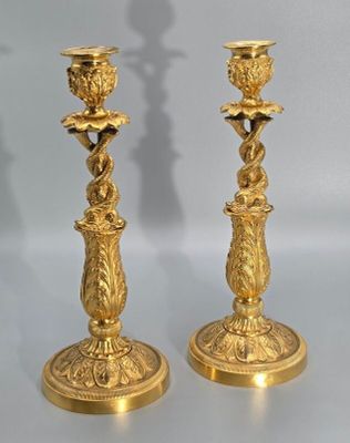 pair of antique brass candlesticks on a table with a shadow of a person