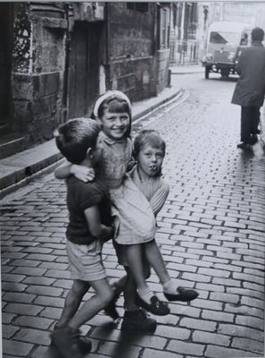 photographie en noir et blanc d'un groupe d'enfants jouant dans une rue pavée