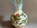 a small vase with a bird on it sitting on a table
