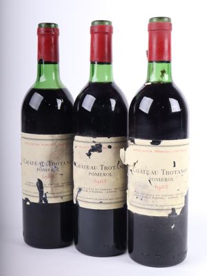 trois bouteilles de vin rouge sont posées les unes à côté des autres sur une surface blanche