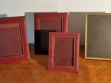 three different colored frames are sitting on a wooden floor