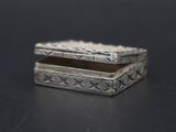 une petite boîte en argent posée sur une surface noire