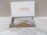 guess shoes in a box on a bed with a white sheet