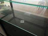 a remote control sitting on a glass shelf in front of a window
