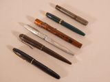 several pens are lined up in a row on a white surface