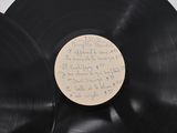 two black vinyl records with writing on them sitting on a table