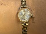 une personne porte au poignet une montre en or sur fond bleu