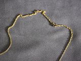 a close up of a necklace with a gold chain on a gray surface