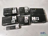 four boxes of black electronic devices sitting on top of a white table