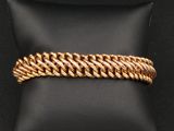 un bracelet plaqué or posé sur un coussin noir