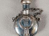 a silver flaskt with a cross on it on a chain