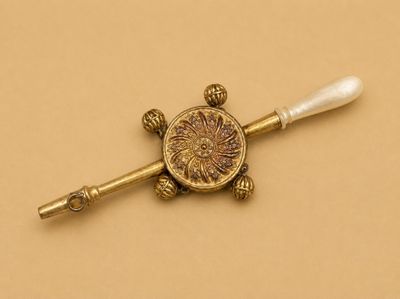 une photo d'une broche en or et perles posée sur une surface marron