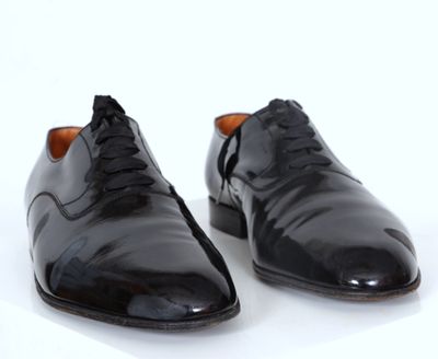 paire de chaussures en cuir noir sur une surface blanche avec un fond blanc