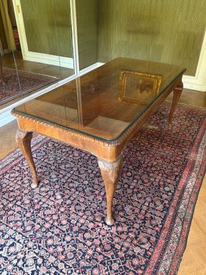 une table en verre avec un piètement en bois posée sur un tapis