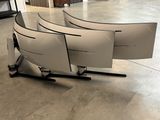 four computer screens sitting on a stand in the middle of a room