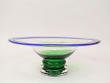 un bol en verre vert bordé de bleu, posé sur un socle