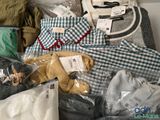 a pile of clothes and a teddy bear sitting on a bed