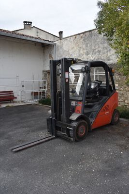 un chariot élévateur garé sur un parking à côté d'un bâtiment