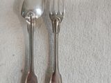 deux cuillères en argent et une fourchette posées sur une nappe blanche
