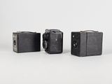 three old cameras sitting next to each other on a white surface