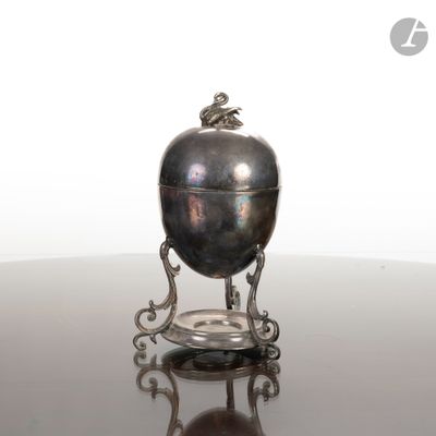 un objet argenté posé sur une table, sur fond blanc