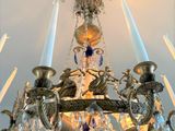 a chandelier with candles and a blue vase on it
