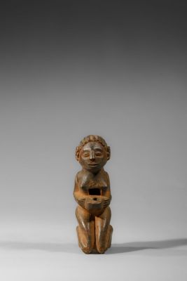 une figurine en bois représentant un enfant tenant un bol