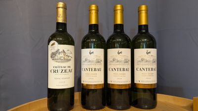 four bottles of wine are lined up on a wooden barrel