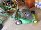 une tondeuse à gazon verte posée par terre à côté d'un vélo
