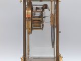 an antique clock with a pendulum and a glass case on a stand