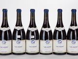 six bottles of wine are lined up in a row on a white surface