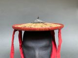 un chapeau posé sur la tête d'un mannequin, entouré d'une écharpe rouge