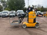 une petite machine jaune garée sur la terre battue