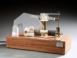 une petite maquette de machine à vapeur posée sur un socle en bois