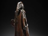a bronze statue of a woman in a cloak holding a staff