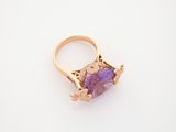 a close up of a gold ring with a purple stone