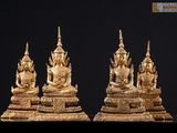 trois statues en or représentant des bouddhas assis sur un socle noir