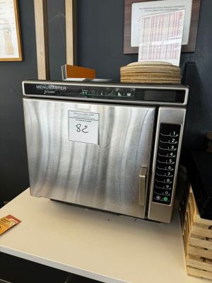 un micro-ondes argenté posé sur un plan de travail blanc