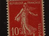 un timbre rouge et noir sur lequel figure une femme en robe
