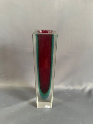 un vase en verre rouge et vert posé sur une table