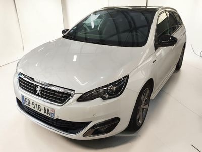 La voiture blanche est garée dans le showroom, tous phares allumés.